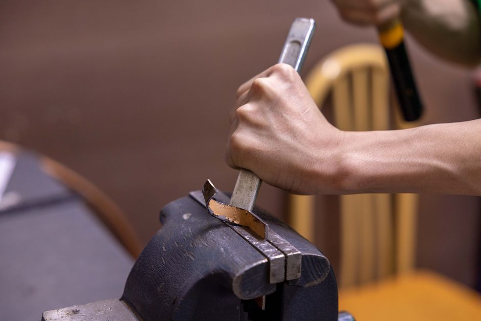 An Indian artisan hand-hammering a metal bowl at a workshop bench