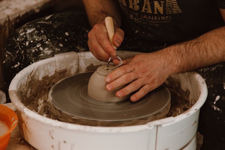 An artisan's hands shaping clay pottery on a wheel